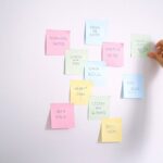 kobieta przyklejająca sticky notes do ściany
