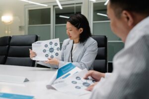 Kobieta w marynarce pokazuje współpracownikowi wydruk z diagramem dotyczącym newslettera.